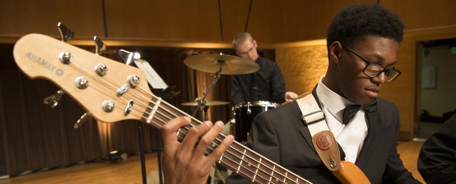 Student playing in a guitar in a concert.